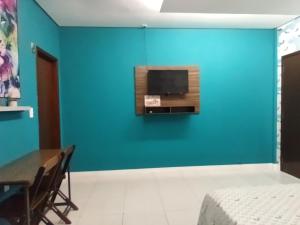 um quarto com uma parede azul com uma televisão e uma mesa em Quarto Nostalgia em Rio Branco