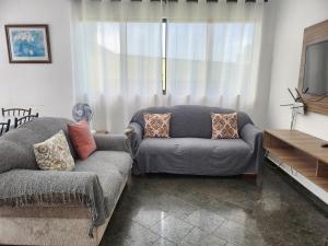 uma sala de estar com um sofá e uma televisão em Triplex Enseada Guarujá no Guarujá