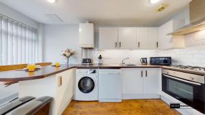 eine Küche mit weißen Schränken, einer Waschmaschine und einem Trockner in der Unterkunft Cardiff centre flat with free parking in Cardiff