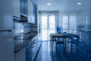 a blue kitchen with a sink and a table at Puente Romana in San Ciprián
