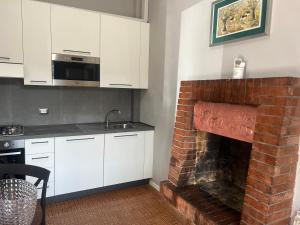 a kitchen with white cabinets and a brick fireplace at IL TORRIONE in Castel Bolognese