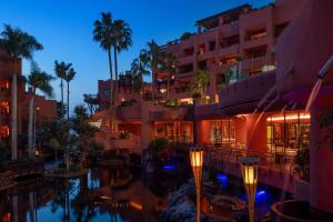 a hotel with a pool and palm trees at night at The Ritz-Carlton Tenerife, Abama in Guía de Isora
