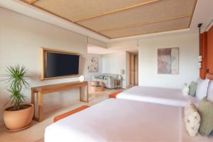 a bedroom with a white bed and a flat screen tv at The Ritz-Carlton Tenerife, Abama in Guía de Isora