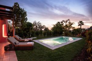 a swimming pool in a yard with a couch and a chair at The Ritz-Carlton Tenerife, Abama in Guía de Isora