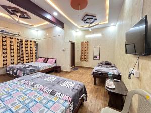 Habitación con 2 camas y TV de pantalla plana. en Ashirwad Holiday Homes, en Ujjain