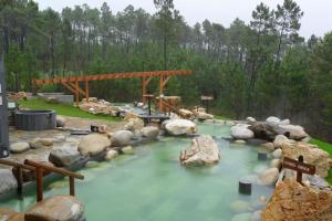 una piscina de agua con rocas y un puente de madera en casa ribeiro, en Ribadavia