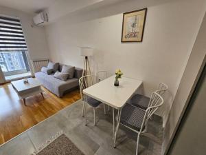 een woonkamer met een tafel en stoelen en een bank bij Milo Apartment in Skopje