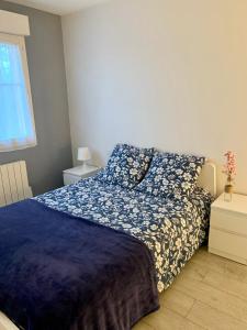 a bedroom with a bed with a blue comforter and a window at Grand F3 - Emplacement d'or proche Paris et Versailles in Plaisir