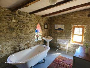 a bathroom with a bath tub and a sink at Phils Cottage in Kenmare