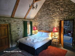 a bedroom with a bed and a stone wall at Phils Cottage in Kenmare
