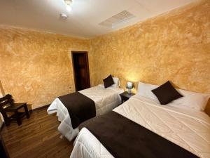 two beds in a hotel room with yellow walls at NASS Central Garden in Cuenca