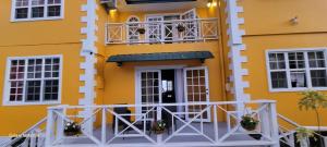 a yellow building with a balcony in front of it at Faith's Villa Tobago in Diamond