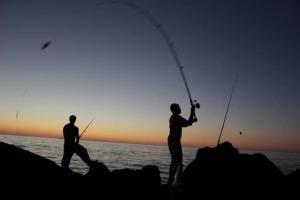 Due uomini che pescano sulla spiaggia al tramonto di Curlews Rest - Gateway to the Aran Islands a Galway