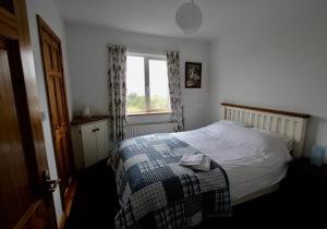 una camera da letto con un letto con una coperta e una finestra di Curlews Rest - Gateway to the Aran Islands a Galway