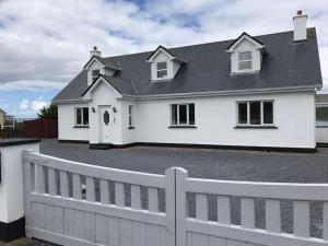 een wit huis met een wit hek bij Curlews Rest - Gateway to the Aran Islands in Galway
