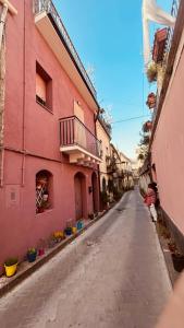 uma rua vazia ao lado de um edifício cor-de-rosa em Sabbenerica em Linguaglossa