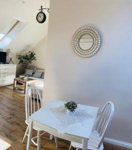 een tafel en stoelen in een woonkamer met een klok bij Bursztynowa komnata - apartament in Gdańsk