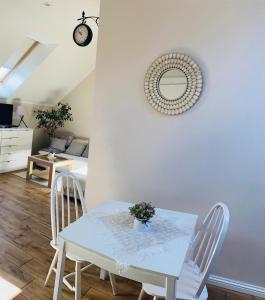 a table and chairs in a living room with a clock at Bursztynowa komnata - apartament in Gdańsk