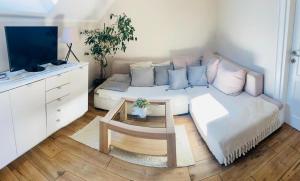 a living room with a white couch and a tv at Bursztynowa komnata - apartament in Gdańsk