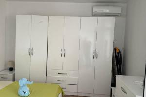 - une chambre avec des armoires blanches et un ours en peluche assis sur un lit dans l'établissement BS Apartment 5, à Durrës