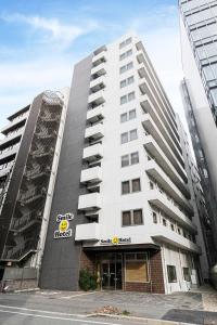 un edificio blanco alto con un letrero. en Smile Hotel Hakataekimae en Fukuoka