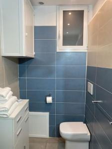 uma casa de banho em azulejos azuis com um WC e uma janela em casa vacanze Luca intero alloggio em Catânia