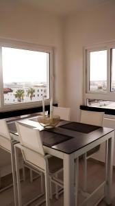 a dining room with a table and chairs and two windows at Appartement marina agadir in Agadir