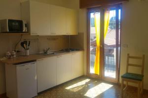 una cocina con armarios blancos y una puerta corredera de cristal en Casa Rosa sopra la Costiera, en San Lazzaro Agerola