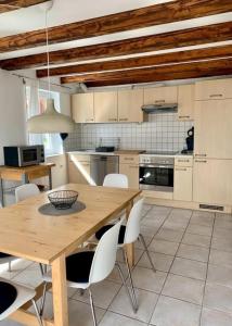cocina con mesa de madera y sillas blancas en Haus Alkmene en Bodman-Ludwigshafen