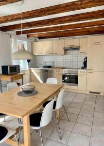 Una cocina con una mesa de madera y sillas blancas. en Haus Alkmene, en Bodman-Ludwigshafen