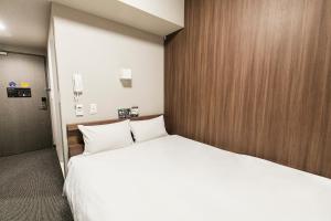 1 dormitorio con 1 cama blanca grande y paredes de madera en Smile Hotel Hakataekimae en Fukuoka