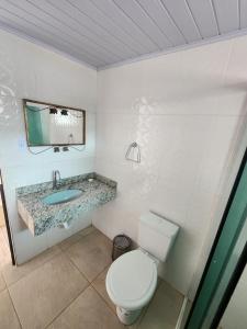 a bathroom with a toilet and a sink and a mirror at Residencial Silveira in Itajaí