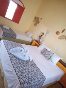 a hotel room with two beds and a window at POUSADA LUATOUR Praia Pontal do Coruripe in Coruripe