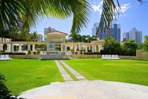 a large building with a green yard with white benches at Mantra Towers of Chevron in Gold Coast