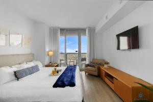 a bedroom with a bed and a television and a couch at Upper Beachwalk Condo Amazing Balcony View in Hallandale Beach