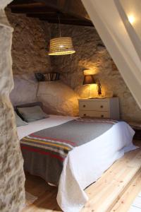 une chambre avec un lit dans un mur de pierre dans l'établissement Lugar São Salvador de Monsanto, à Monsanto
