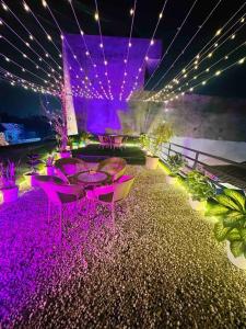 a patio with purple lights and tables and plants at The Grey House! in Noida
