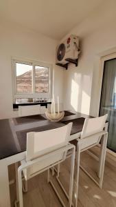 a dining room with two white chairs and a table at Appartement marina agadir in Agadir