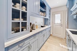 uma cozinha com armários brancos e paredes azuis em Seafront, Luxury 2-BDR Townhouse em Andros