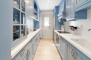 a kitchen with blue cabinets and white counters at Seafront, Luxury 2-BDR Townhouse in Andros