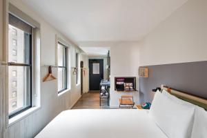 a bedroom with a bed and a hallway with a desk at MOXY NYC Times Square in New York