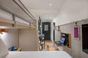 a bedroom with a bed and a desk with a laptop at MOXY NYC Times Square in New York