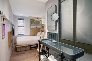 a bathroom with a sink and a bed in a room at MOXY NYC Times Square in New York