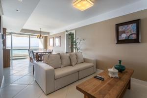 uma sala de estar com um sofá e uma mesa em Varanda com Churrasqueira e Vista MAR #CHA06 em Florianópolis