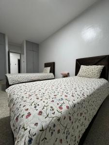 - une chambre avec 2 lits avec un couvre-lit floral dans l'établissement comfortable home, à Aït Saïd