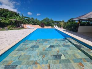 una piscina con suelo de baldosa y una casa en Villa MONOIHERE, en Mahina