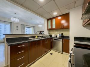 a large kitchen with wooden cabinets and a sink at JBR Beach, The Walk, 1-BDR with pool view in Dubai