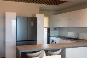 a kitchen with a black refrigerator and white cabinets at Aqua Mare Luxury Apartments in Paralia Katerinis