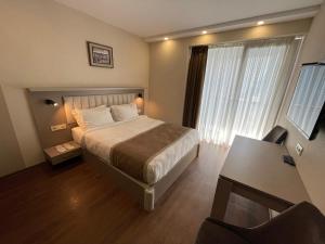 sypialnia z łóżkiem, biurkiem i oknem w obiekcie Poseidon Apartments Batumi w mieście Batumi