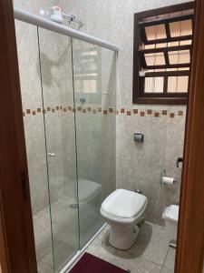 La salle de bains est pourvue de toilettes et d'une douche en verre. dans l'établissement Casa do lado da praia, 100 metros da praia., à Mongaguá